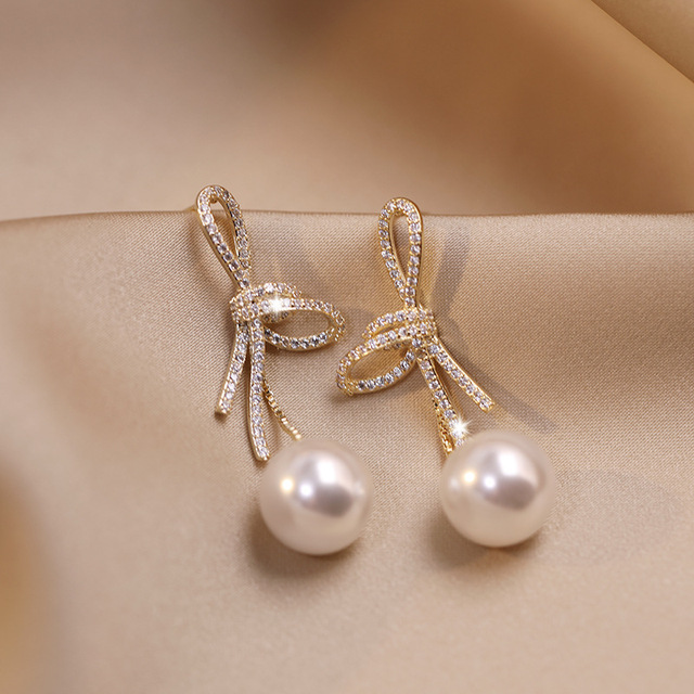 Pendientes de perlas con un lazo brillante en oro